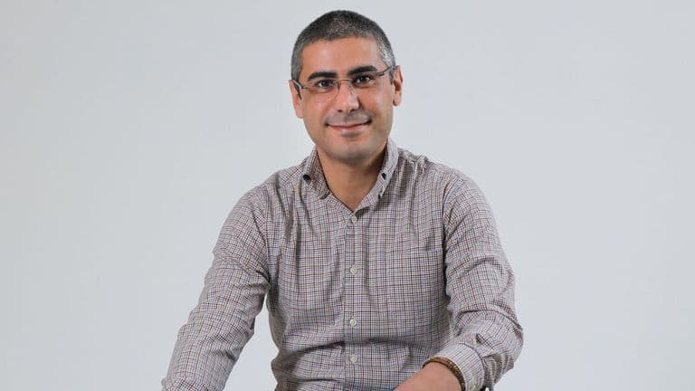 Portrait of entrepreneur and business coach Jad Atwe smiling against a plain gray background.
