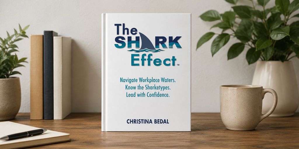 Cover of The Shark Effect by Christina Bedal displayed on a desk beside books, plants, and a coffee mug.