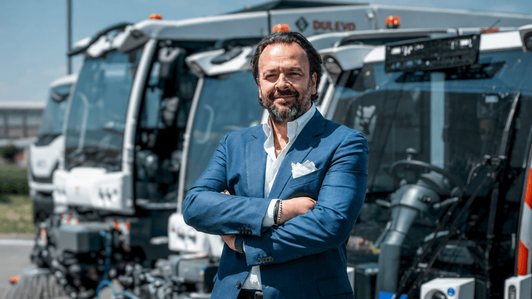 Umberto Maria Cini standing before Dulevo street sweepers at the company's manufacturing facility in Italy.