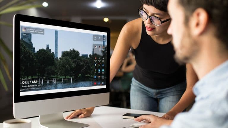 Two people collaborate on the SMARTbranding Chrome Extension in an office, with a serene Central Park view on the screen.