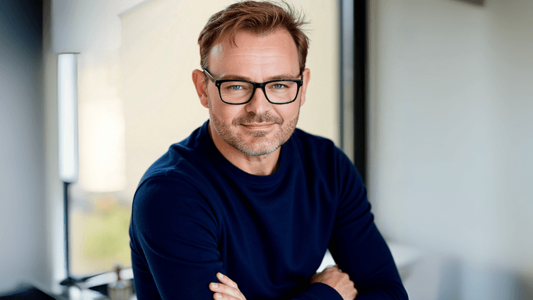"Portrait of a smiling man wearing glasses, a navy blue sweater,