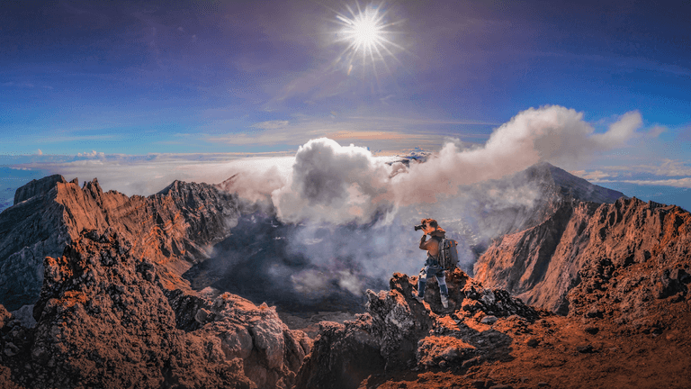"Photographer capturing volcanic landscape with Two Red Tabs backpack, designed for travel and adventure photography."