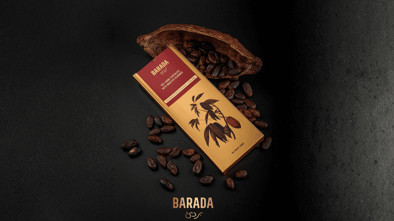 BARADA dark chocolate bar with almonds, surrounded by cacao beans and pod, on a dark background.