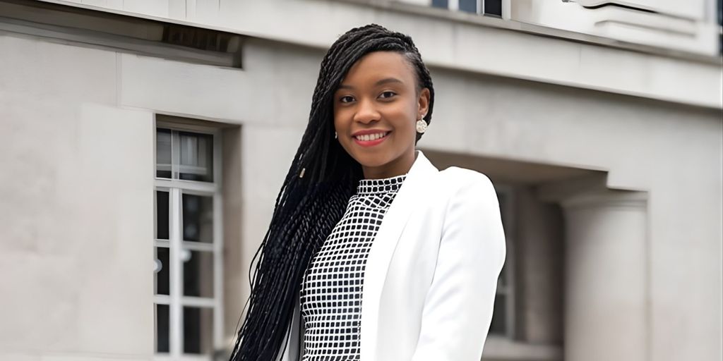 Dr. Amanda Mwale, founder of Resourced to Thrive, smiling confidently in a professional white blazer against a neutral background.