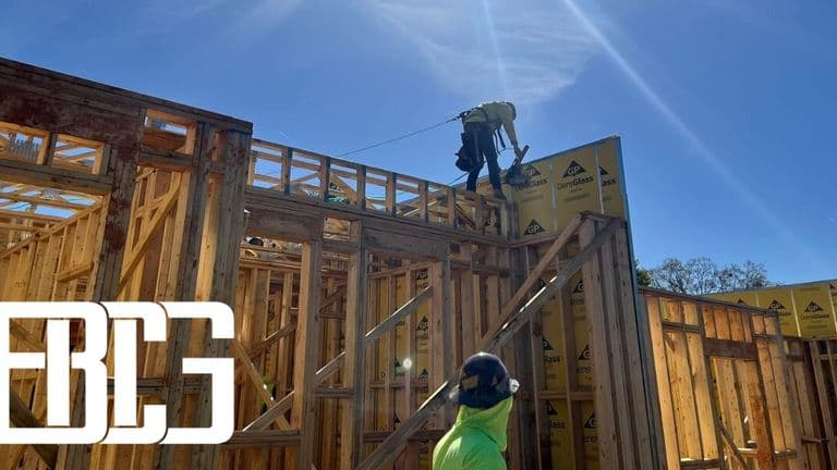Two individuals engaged in construction work on a house, showcasing Bowser Construction Group's commitment to efficiency.