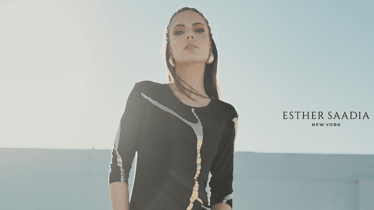 Elegant woman wearing a black modest dress with metallic accents, photographed outdoors in soft natural sunlight.
