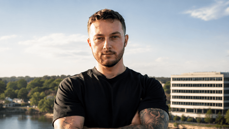 Josh Norris standing outdoors with arms crossed overlooking a city skyline.
