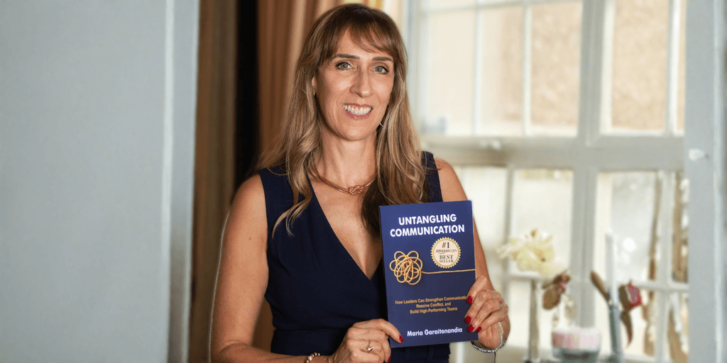 Maria Garaitonandia holding her book, Untangling Communication, promoting her expertise in leadership communication.