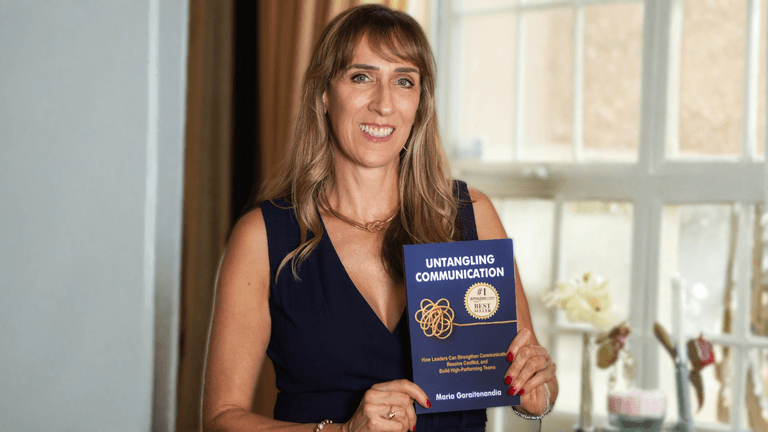Maria Garaitonandia holding her book, Untangling Communication, promoting her expertise in leadership communication.