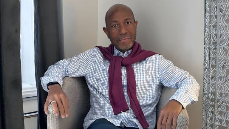 Dr. P. Ernest Parker, Jr., seated with a maroon sweater draped over his shoulders, exuding confidence in a thoughtful pose.