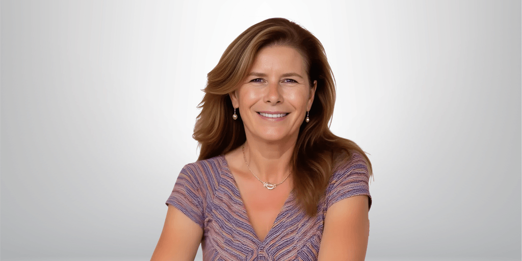 Professional portrait of a smiling woman with shoulder-length brown hair, wearing a purple top and gold earrings, with a soft gradient background.