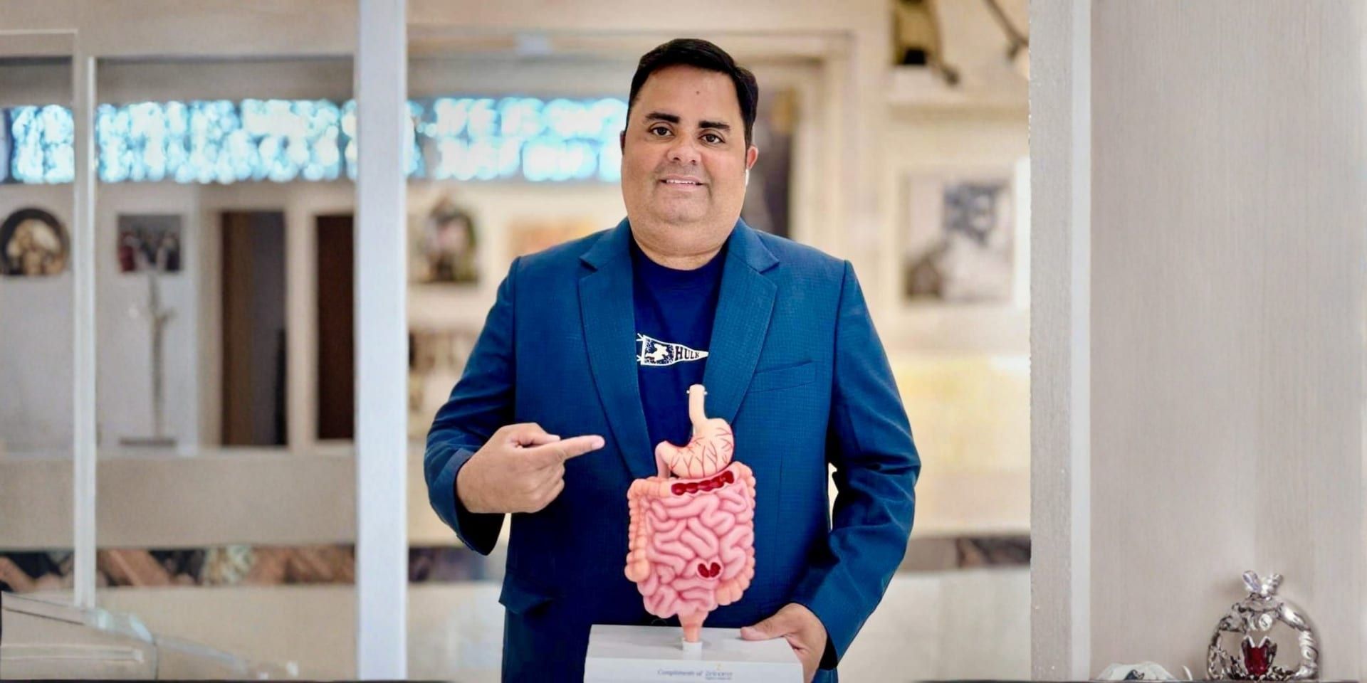 Dr. Rohan Nagar holding a model of the digestive system in his clinic.