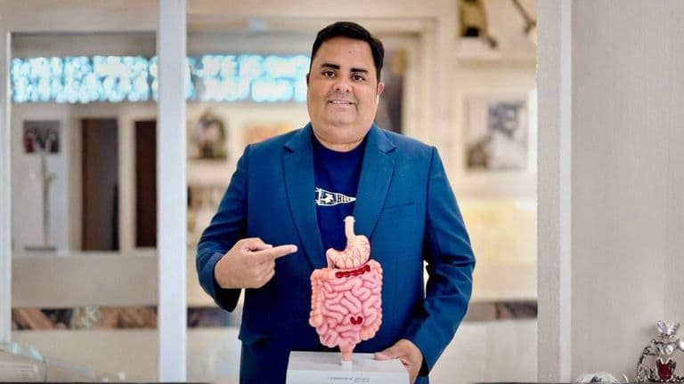 Dr. Rohan Nagar holding a model of the digestive system in his clinic.