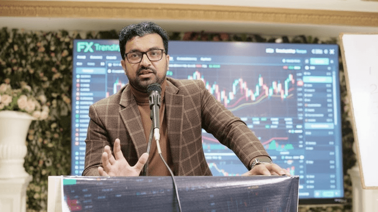 Malik Umar Awan speaking at a forex trading seminar, with AI trading data displayed behind him.