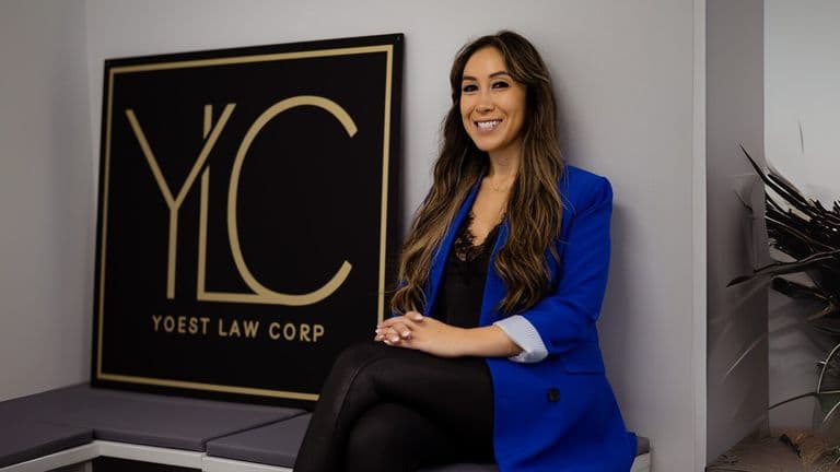 A woman sits on a bench in front of a Yoest Law Corp sign, symbolizing personal legal support and guidance.