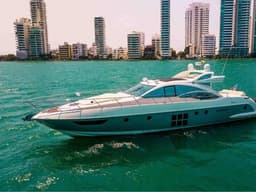 Luxury motor yacht cruising on turquoise water with Cartagena’s high-rise skyline in the background.