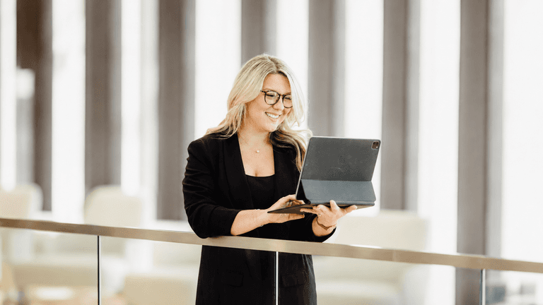 Lauren Foust using a tablet while standing in a modern office workspace.
