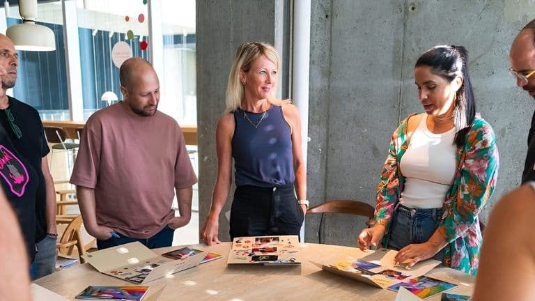A group of people gathered around a table, collaborating and discussing their creative projects.