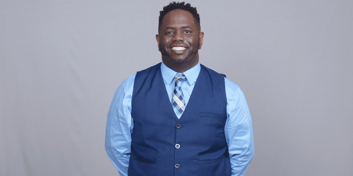 Rashad Woods smiling in a blue vest and tie, founder of The T.R.O.N. Podcast promoting meaningful global conversations.