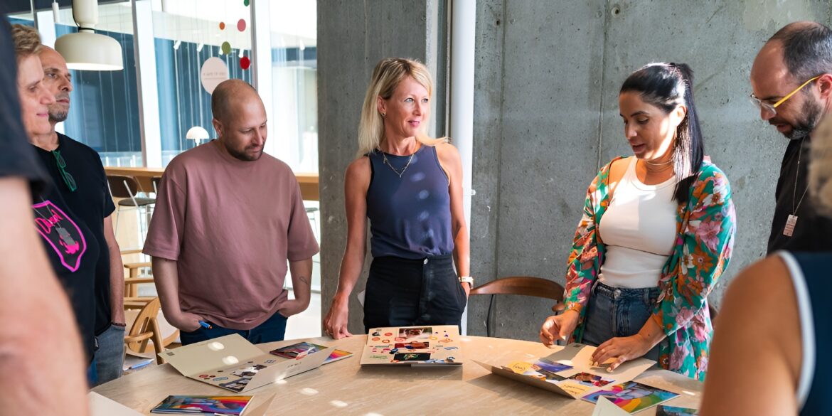 A group of people gathered around a table, collaborating and discussing their creative projects.