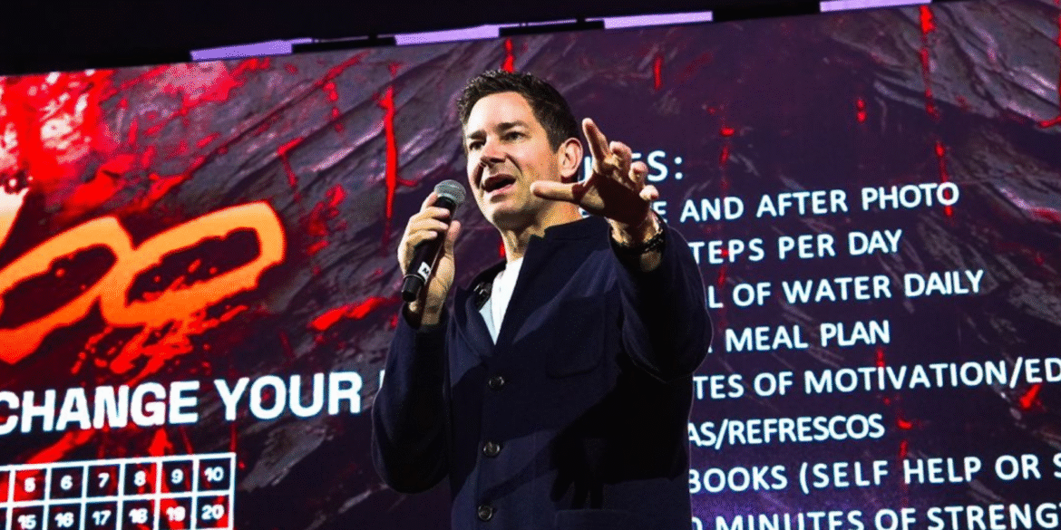 Chad Doetzel speaks on stage about leadership and personal development with motivational text displayed behind him.