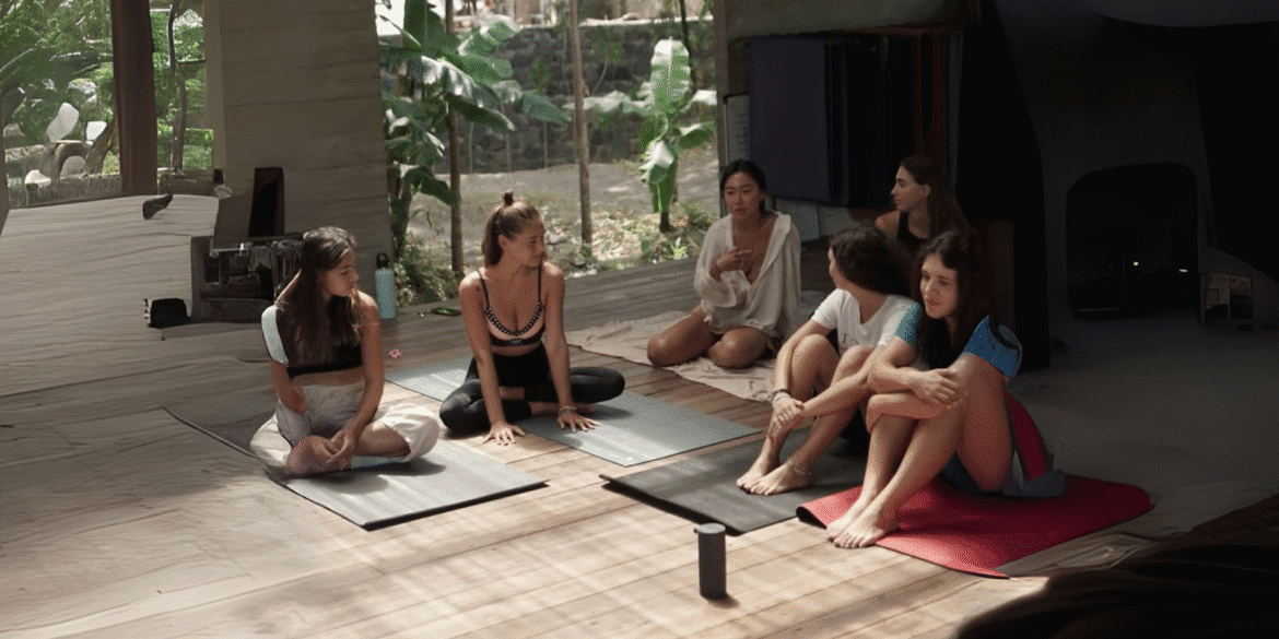 A group of women practicing yoga together in a serene indoor space surrounded by lush greenery, focusing on mindfulness and well-being