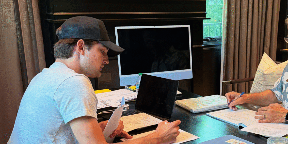 Preston Landes, founder of PL Capital, working with a colleague at a desk, reviewing documents and business plans. The image reflects his hands-on approach to real estate investment and his commitment to mentoring new investors while scaling his business.