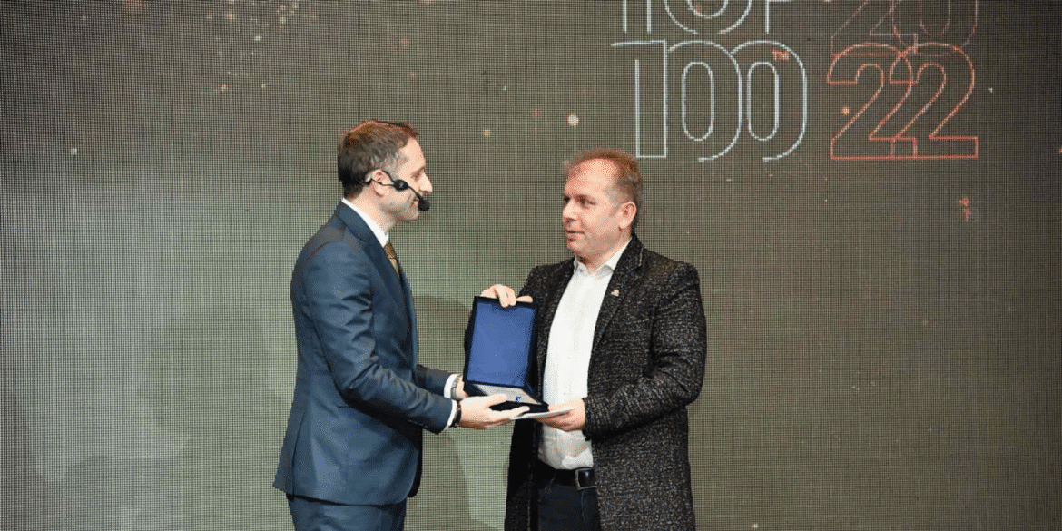 Fejsal Mustafi receiving an award during the Top 100 2022 event, with a presenter handing over the plaque.