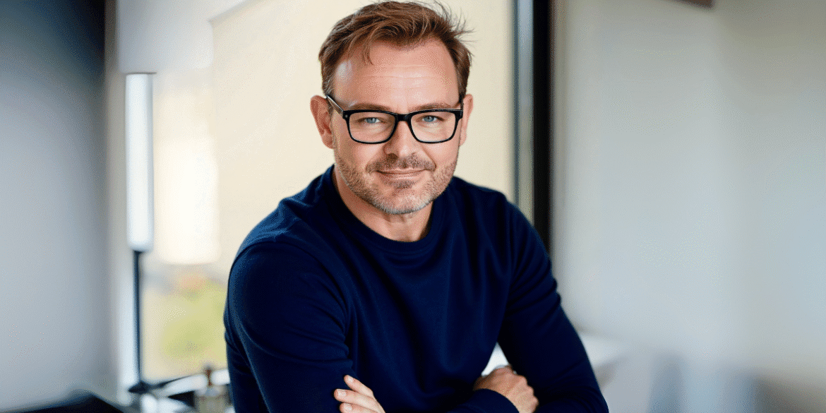 "Portrait of a smiling man wearing glasses, a navy blue sweater,