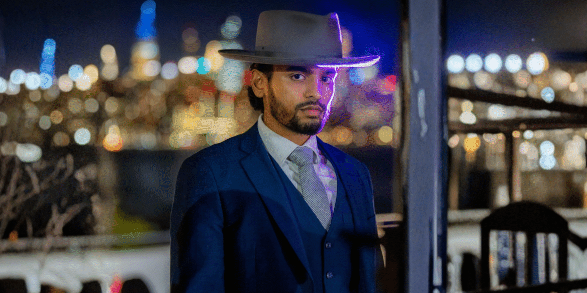 Isaiah Edward in a sharp suit and hat, standing confidently against a blurred cityscape, embodying professionalism and vision.