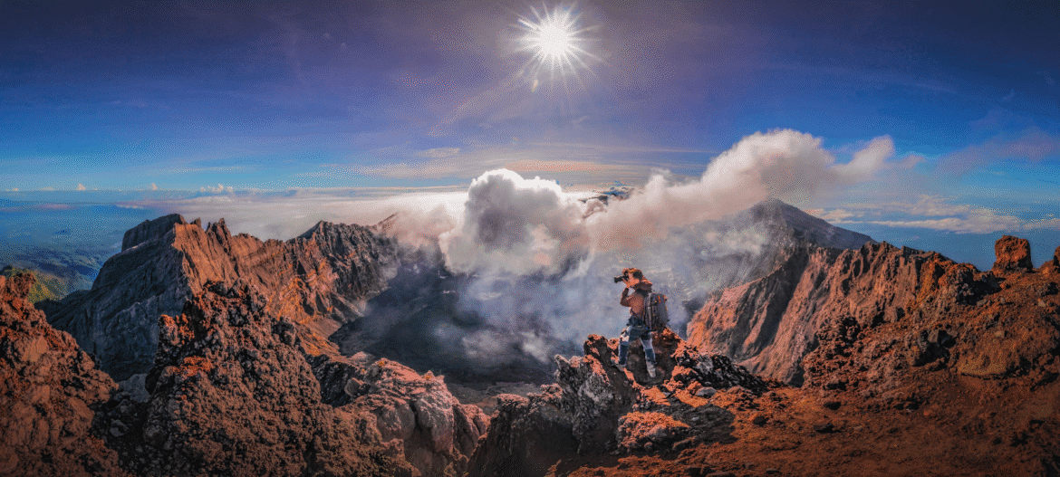 "Photographer capturing volcanic landscape with Two Red Tabs backpack, designed for travel and adventure photography."