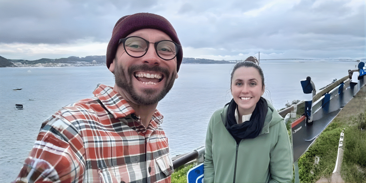 Two smiling people pose by a scenic waterfront viewpoint, representing collaborative leadership and influence from Role Model Leadership.