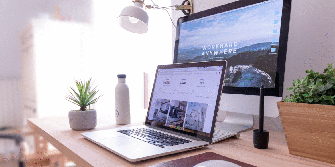 A clean, minimalist desk with a laptop and a motivational AI-related desktop background.