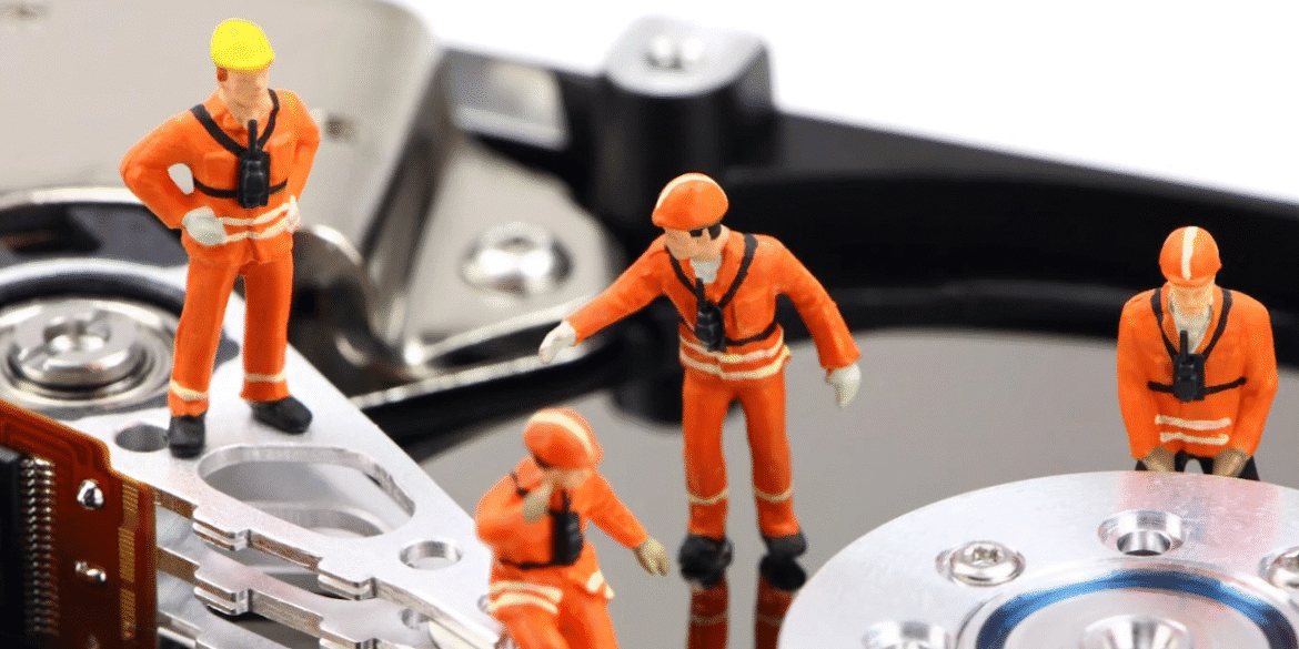 "Miniature construction workers on a hard drive, symbolizing Kelley Information Technology’s hands-on, personalized IT support for small businesses."