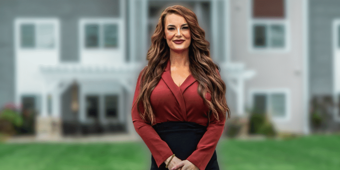 Alexis Anderson stands confidently outside a modern building, showcasing professionalism with her vibrant auburn hair and red attire.