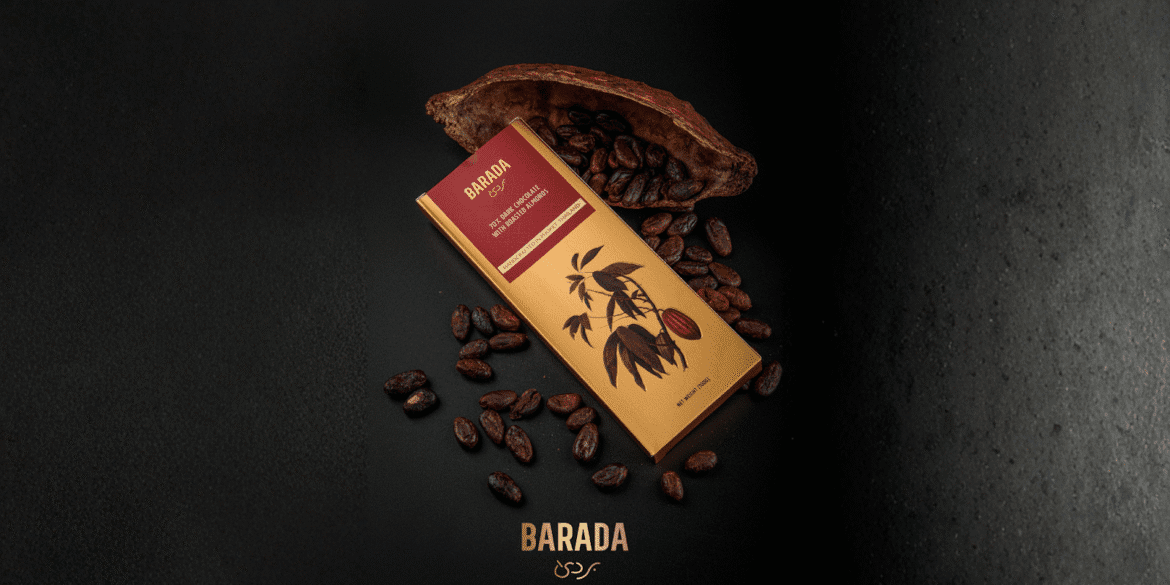 BARADA dark chocolate bar with almonds, surrounded by cacao beans and pod, on a dark background.