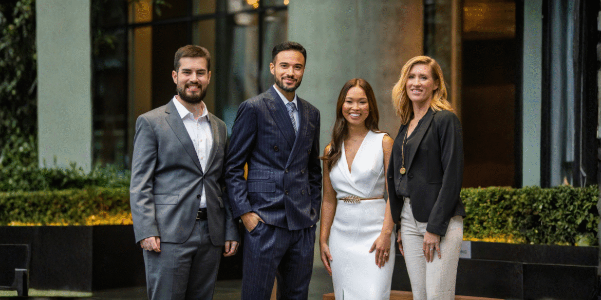 Four professionals in business attire pose outside a modern office building, representing Medallion Investments' team.