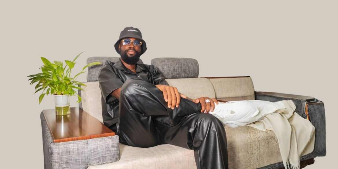 Benjamin Sarpong in stylish black leather attire, seated comfortably with one leg crossed, exuding confidence.