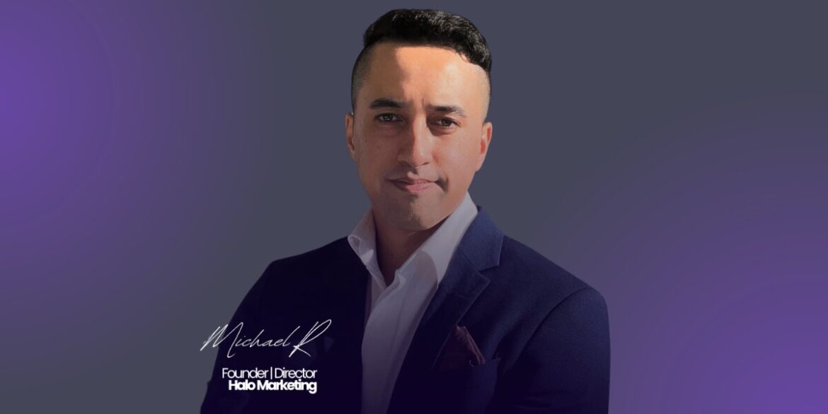 Michael Ripia in a suit and tie stands confidently against a vibrant purple background.