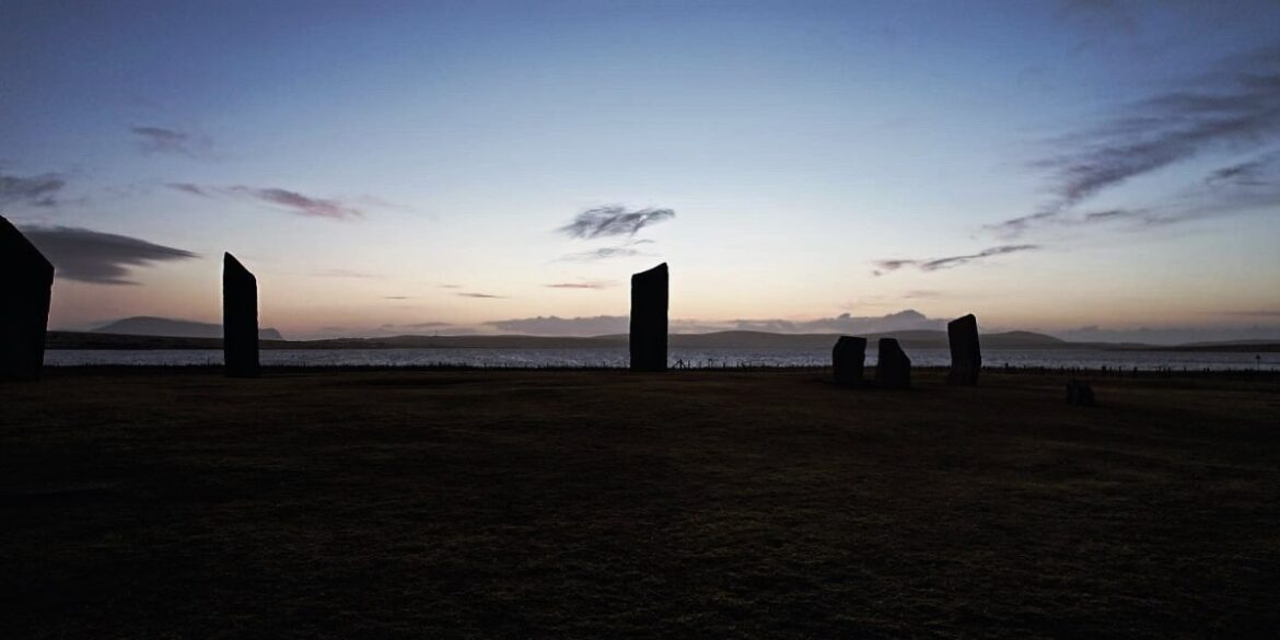 an archaeological site with standing stones against a scenic landscape, reflecting themes of historical exploration and discovery.