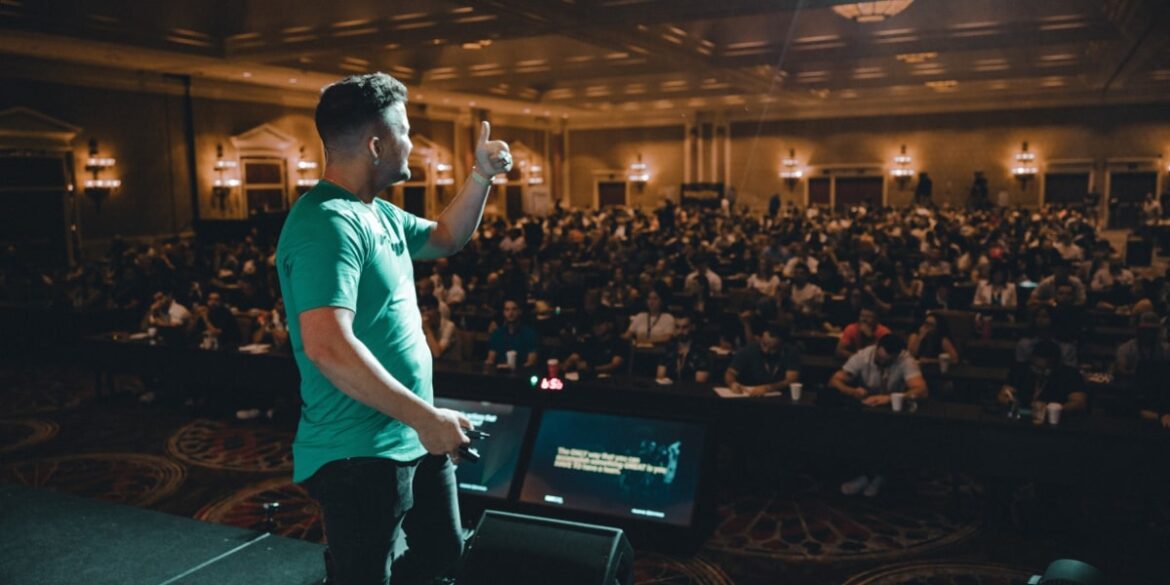 Chris Lee speaking to a large audience at a business event, sharing insights on scaling businesses and leadership.