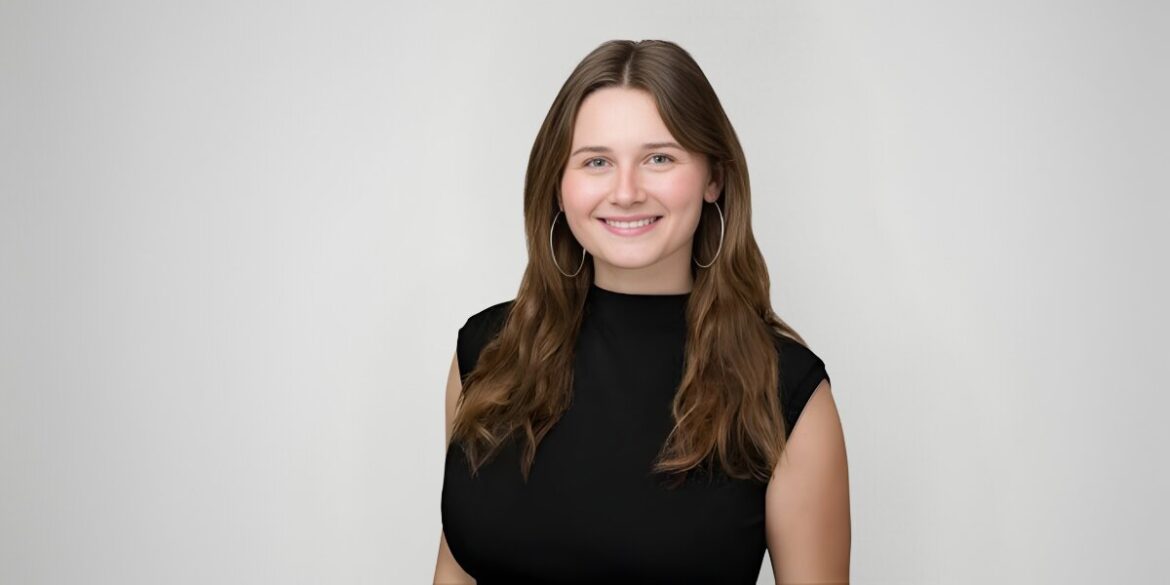 A young woman in a black top smiles confidently, embodying her message of action over intention.