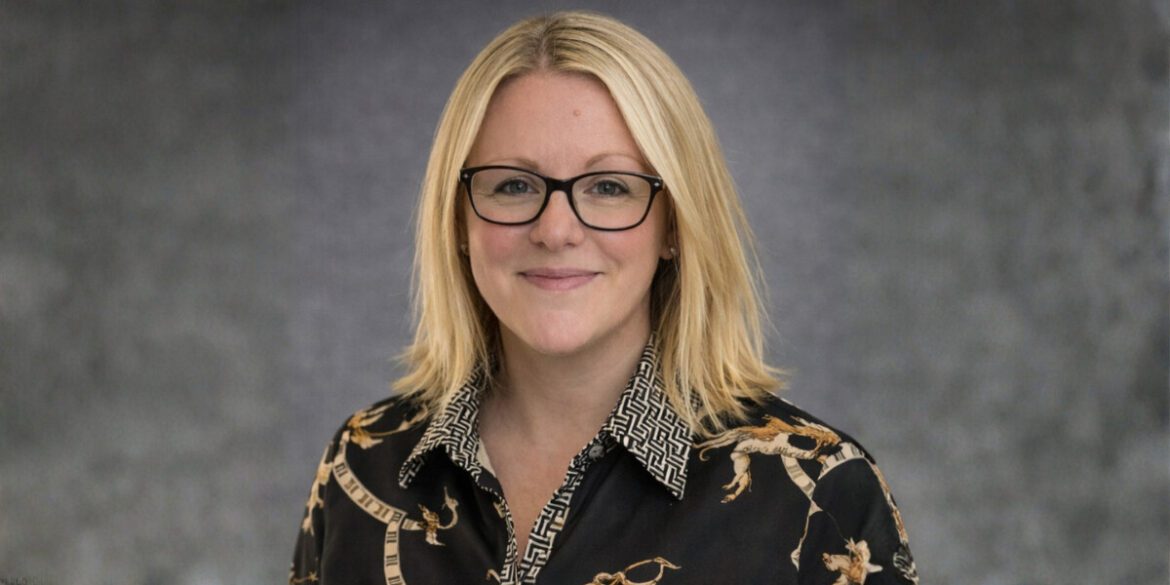Hannah Hally, founder of The Business Book Club, wearing a patterned blouse, smiling confidently with a professional backdrop.