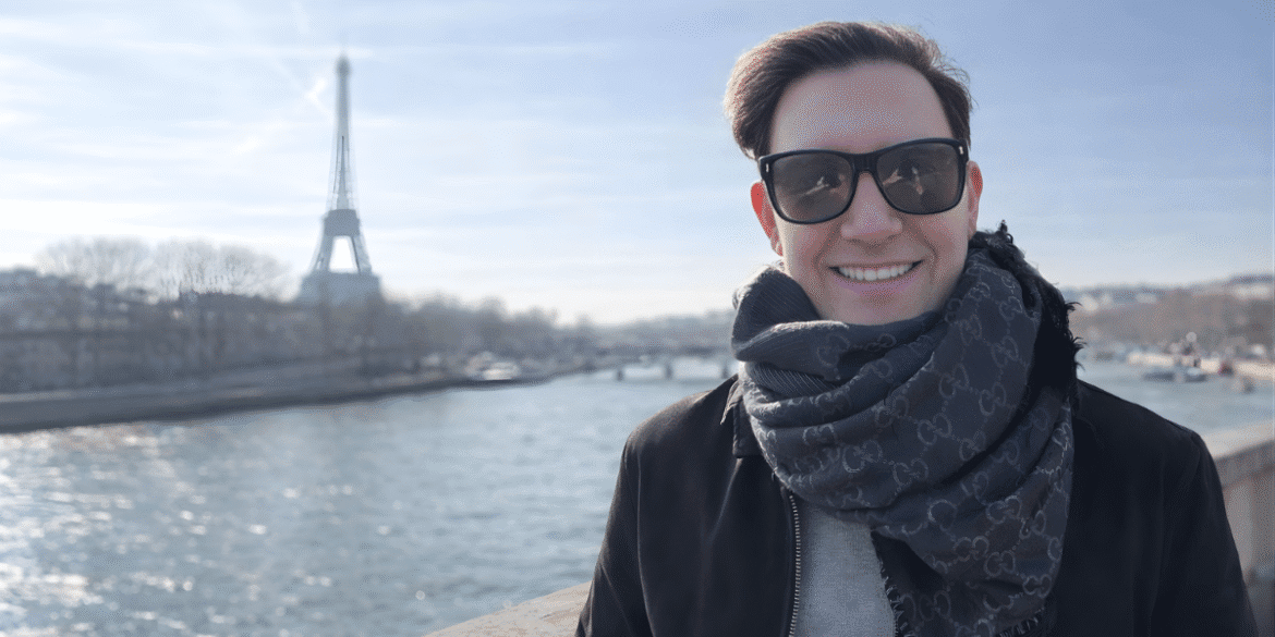 Zach Randles-Friedman smiling with the Eiffel Tower in the background during a visit to Paris.