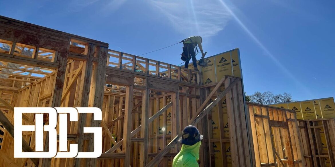 Two individuals engaged in construction work on a house, showcasing Bowser Construction Group's commitment to efficiency.
