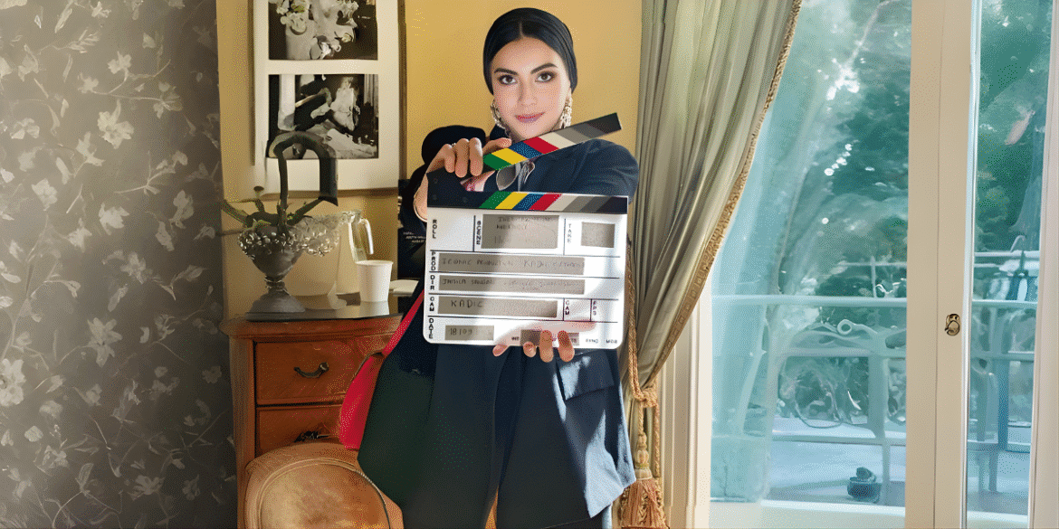 Jamila Sangaré, founder of Iconic Frame Productions, holding a film clapperboard, symbolizing her leadership in cross-cultural cinema.