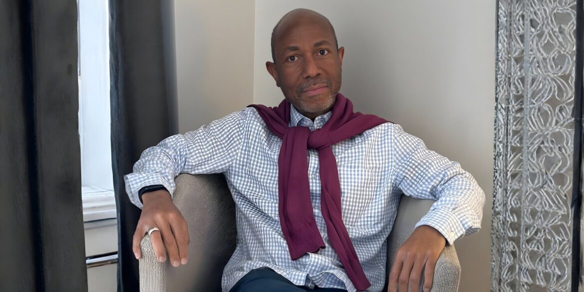Dr. P. Ernest Parker, Jr., seated with a maroon sweater draped over his shoulders, exuding confidence in a thoughtful pose.
