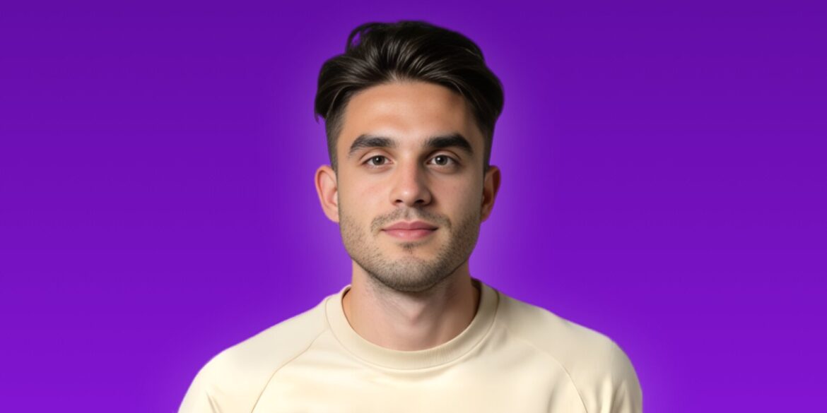A man in a white shirt smiles at the camera, embodying confidence and approachability in a professional setting.
