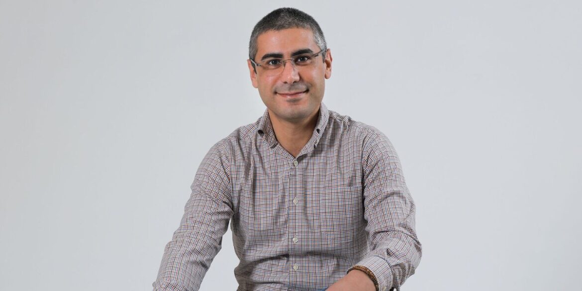 Portrait of entrepreneur and business coach Jad Atwe smiling against a plain gray background.