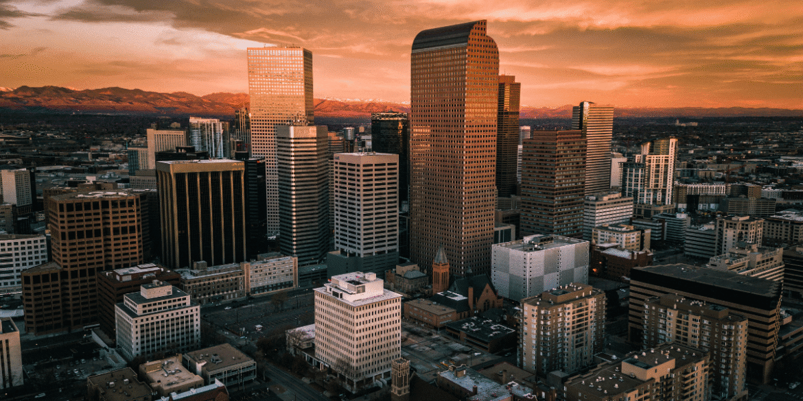 Downtown Denver skyline at sunset with modern skyscrapers and Rocky Mountains in the background
